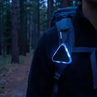 Customer photo — the clip glowing faintly on a strap at dusk
